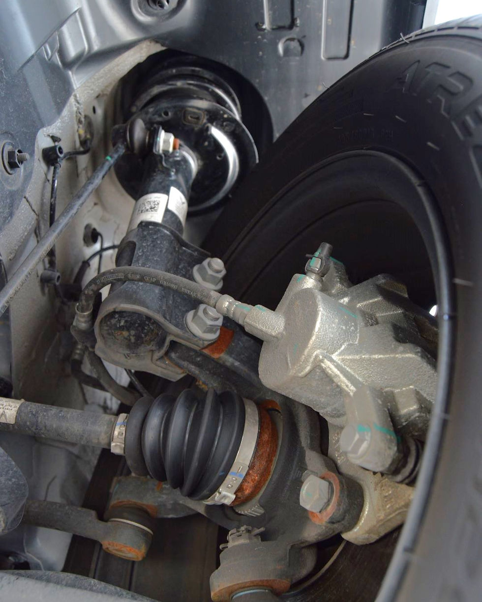 Suspensi depan McPherson Strut.