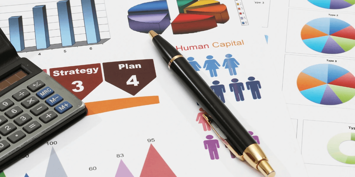 Paper with business infographics printed on. A pen and calculator on top of paper