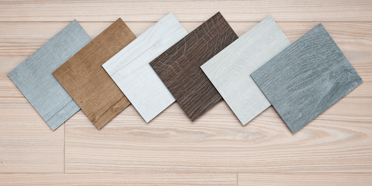 Luxury vinyl tile samples against a light wood floor background