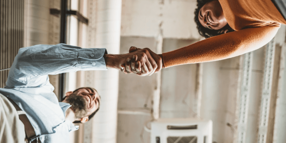 Two people shaking hands and discussing outreach and relationship building