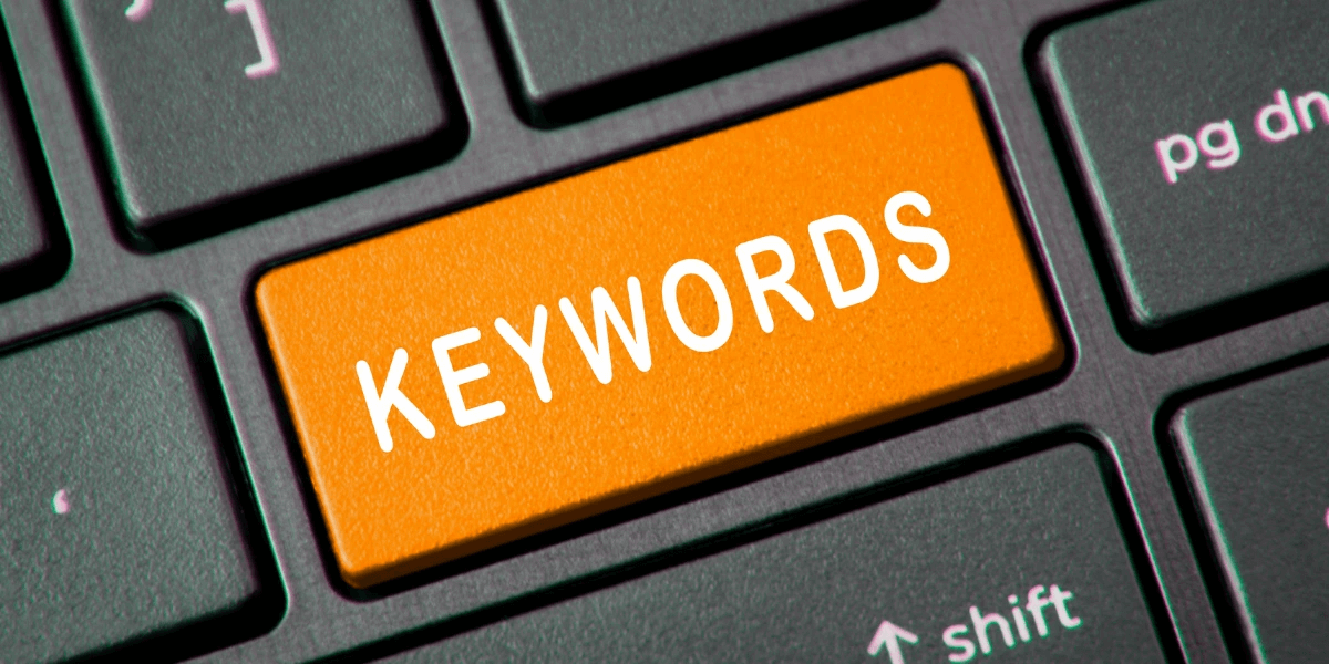 Black computer keyboard with an orange key labeled 'Keywords'