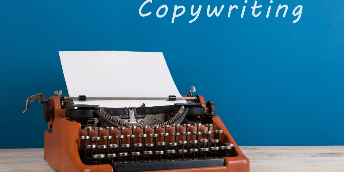 A red typewriter against a blue blackboard that has the word 'Copywriting' written in white chalk