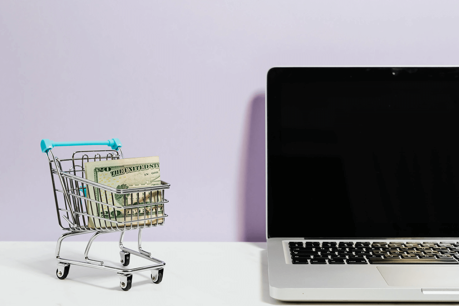 Laptop near a toy cart with money. 