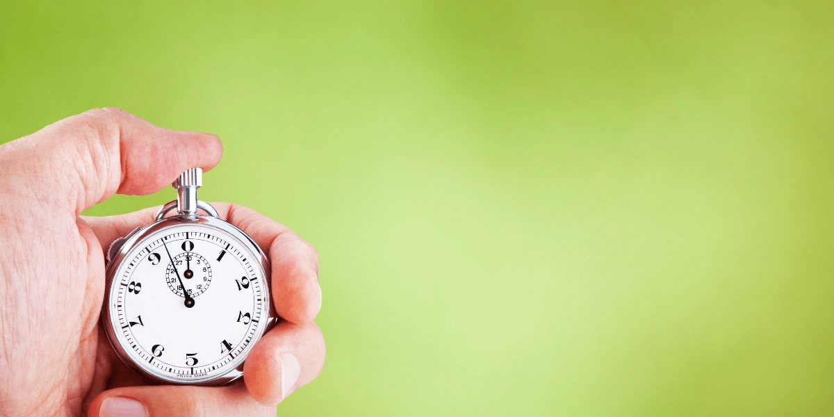 Vintage analog stopwatch in hand against a green background to denote measuring website speed