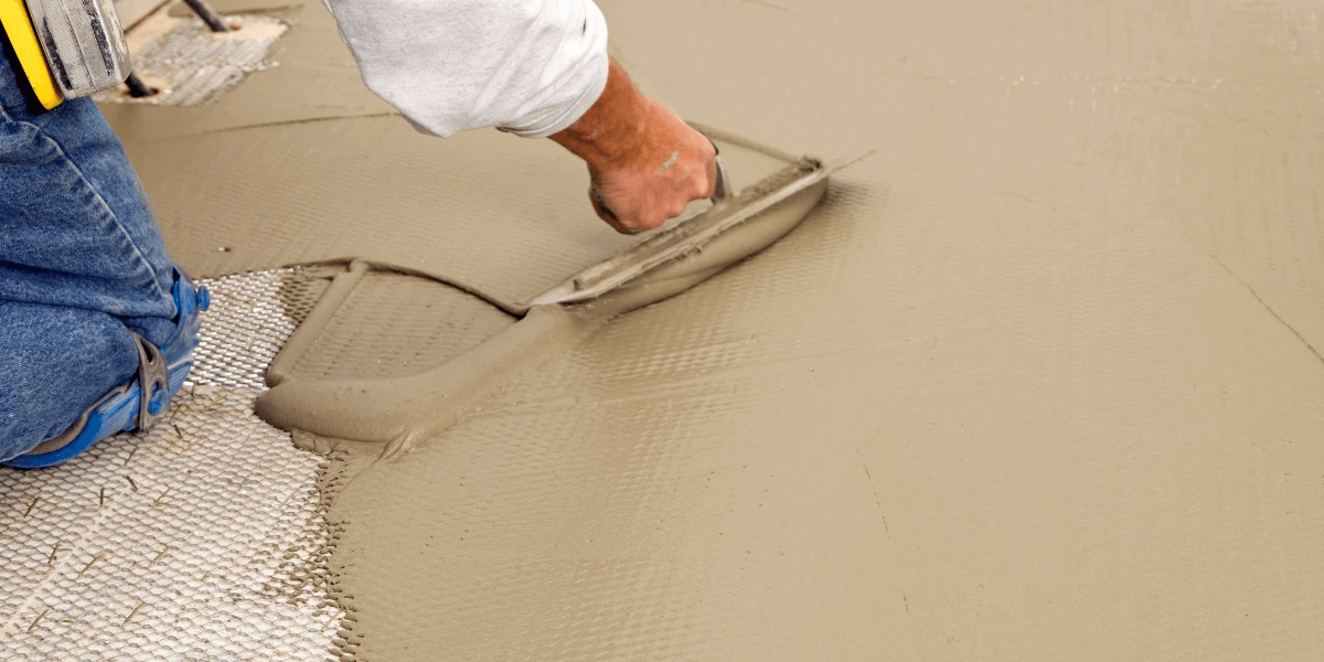 A person troweling mortar for the mesh subfloor to fix holes and prepare it for the luxury vinyl plank