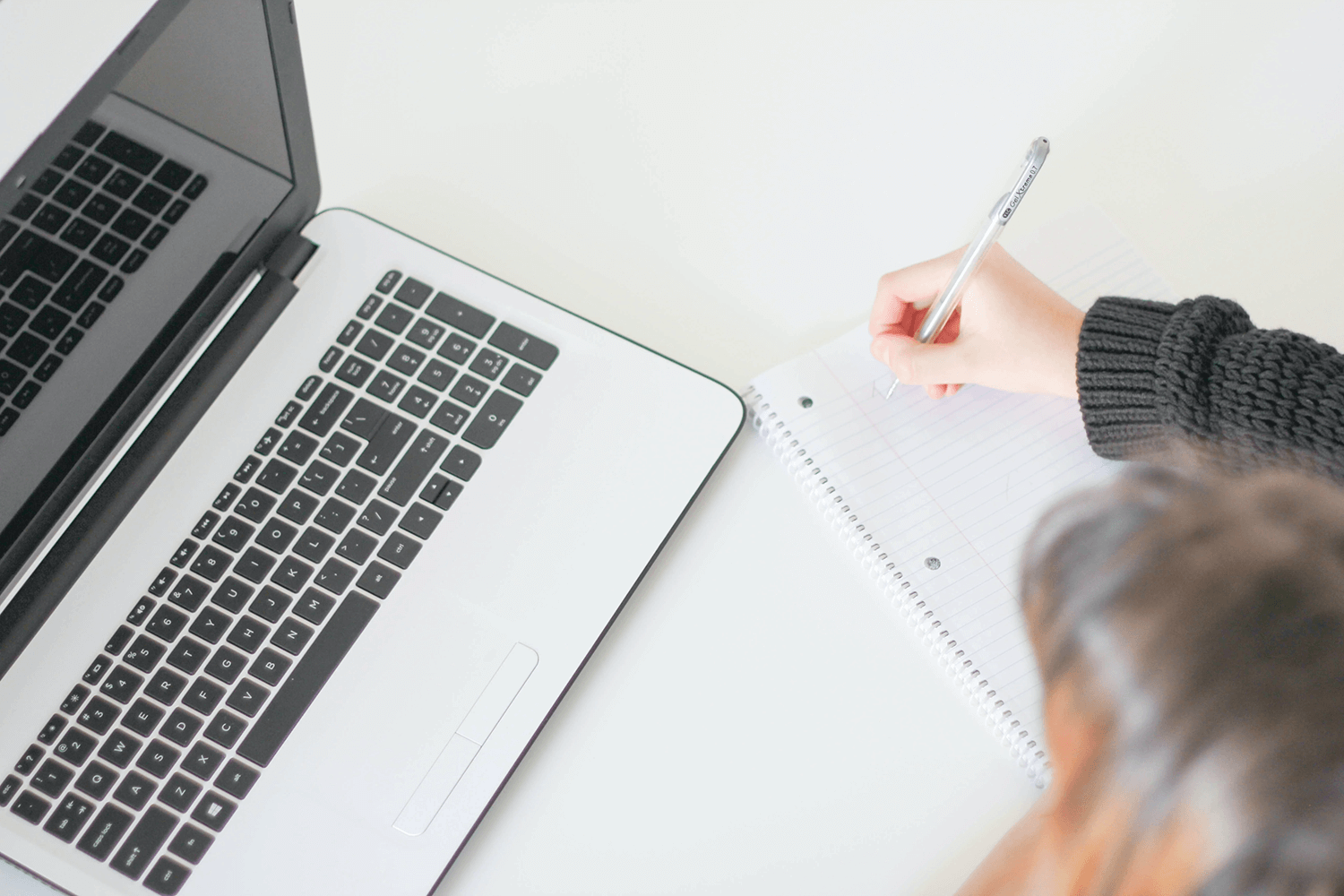 Designer in front of laptop laying out content plans in a notebook