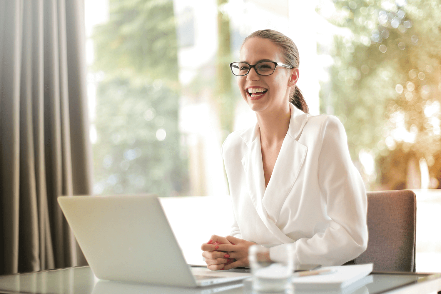 A smiling woman in front of a laptop 