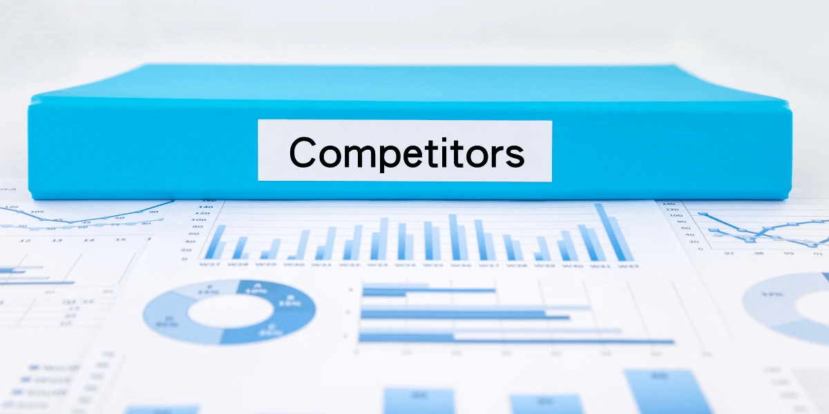 Blue binder with label 'Competitors' placed on top of printed graphs