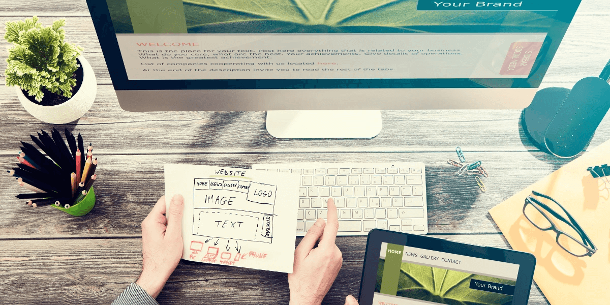 Image of hands holding a paper containing the design of a website that is mobile optimized