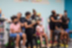 Image of children getting their hair styled by a vendor at a community event.