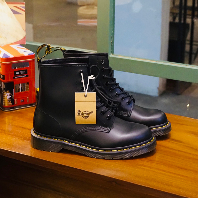 Sepatu dr martens berwarna hitam yang diletakkan di atas meja