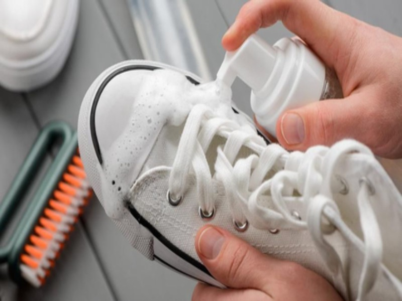 seseorang sedang mencuci sepatu dengan foam cleaner sepatu