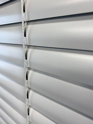 Close-up of white aluminum venetian blinds right after cleaning, part of an office window, providing privacy and light control.