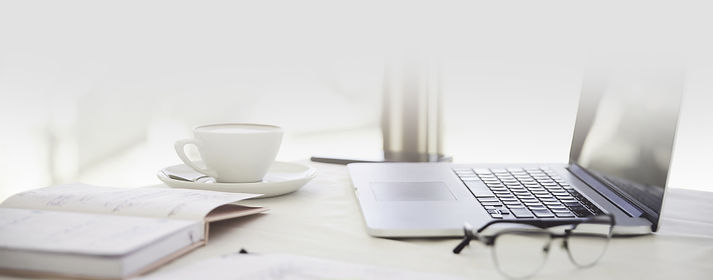 primeiro-plano-lateral-de-uma-mesa-de-trabalho-com-o-laptop-xicara-de-cafe-oculos-e-artigo