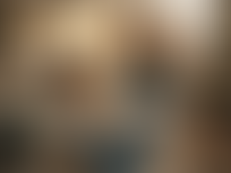 A young child wearing noise-reducing headphones sits on a swing indoors, quietly reading a book. Behind them, people celebrate Christmas in a warm, festive room with soft lights and decorations, creating a cozy contrast between the lively background and the child’s calm sensory-friendly space.