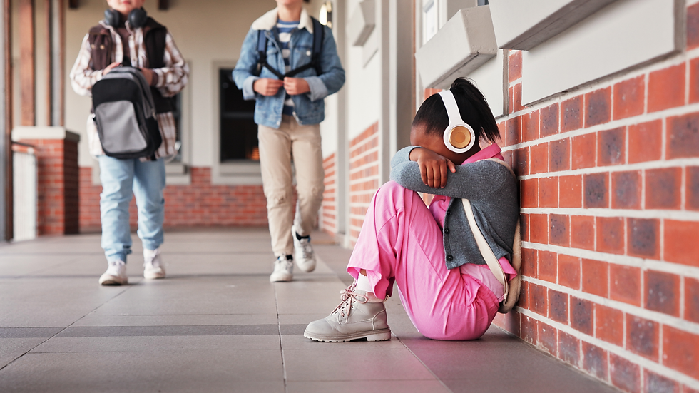 A child sitting crouched against a wall, visibly upset with head in her hands