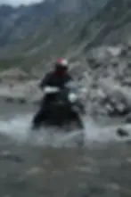 A biker riding through a stream in a mountain.