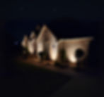 Modern brick home with professional landscape lighting installed by Water Worx highlighting exterior walls and shrubs at night