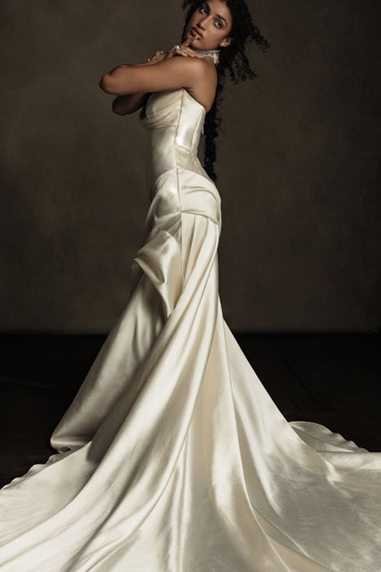 Inspired by the draped elegance of stone sculptures, Scarlette harmoniously blends modern and classical elements. Its structured, bold silhouette is beautifully softened by inserts of flowing boiled chiffon, creating captivating contrast between the sculptural skirt and the fluidity of the fabric. Body-contouring pleats extend from the high hip into a breathtaking train, designed to inspire our contemporary romantics.