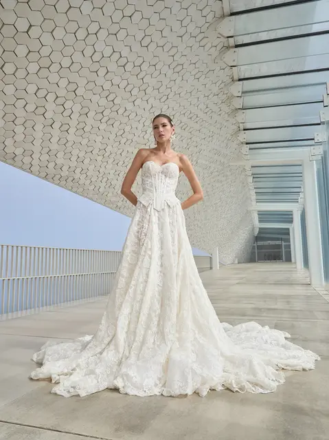 Experience regal drama in this stunning two-piece ball gown, crafted from luxurious corded French lace. The geometrically engineered corset beautifully accentuates every curve, while the rich, voluminous flowing skirt adds a touch of grandeur. Paired with a matching bolero, this ensemble delivers a bold and cohesive statement fit for any royal affair.