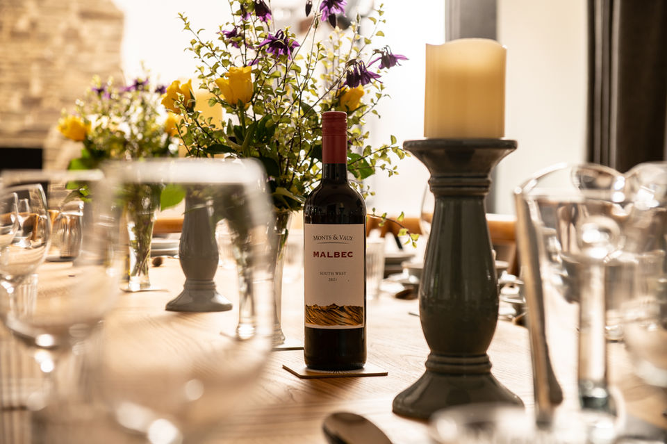 Dining table with wine, glasses, flowers and candles.