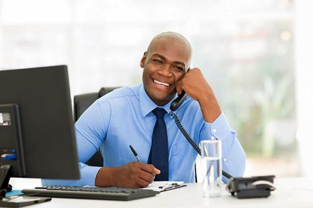 Smiling man in a blue shirt holding a pen, marketing cold calling.