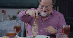 Kevin Farley enjoys a funny Thanksgiving dinner moment in Grumpy Old Santa, smiling as he lifts a tu