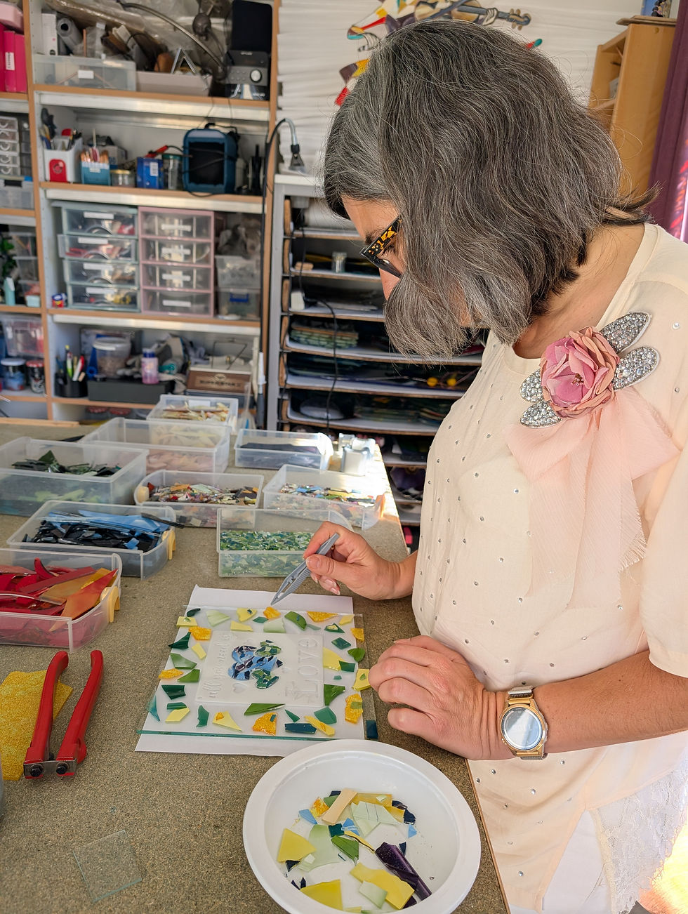 Délicatement, elle coupe ses morceaux de verre et les positionne sur sa feuille de verre.