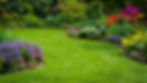 Grass area with curved garden bed full of yellow, red, purple and pink plants