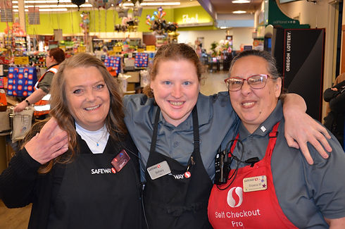 Three smiling Safeway employees at checkout.