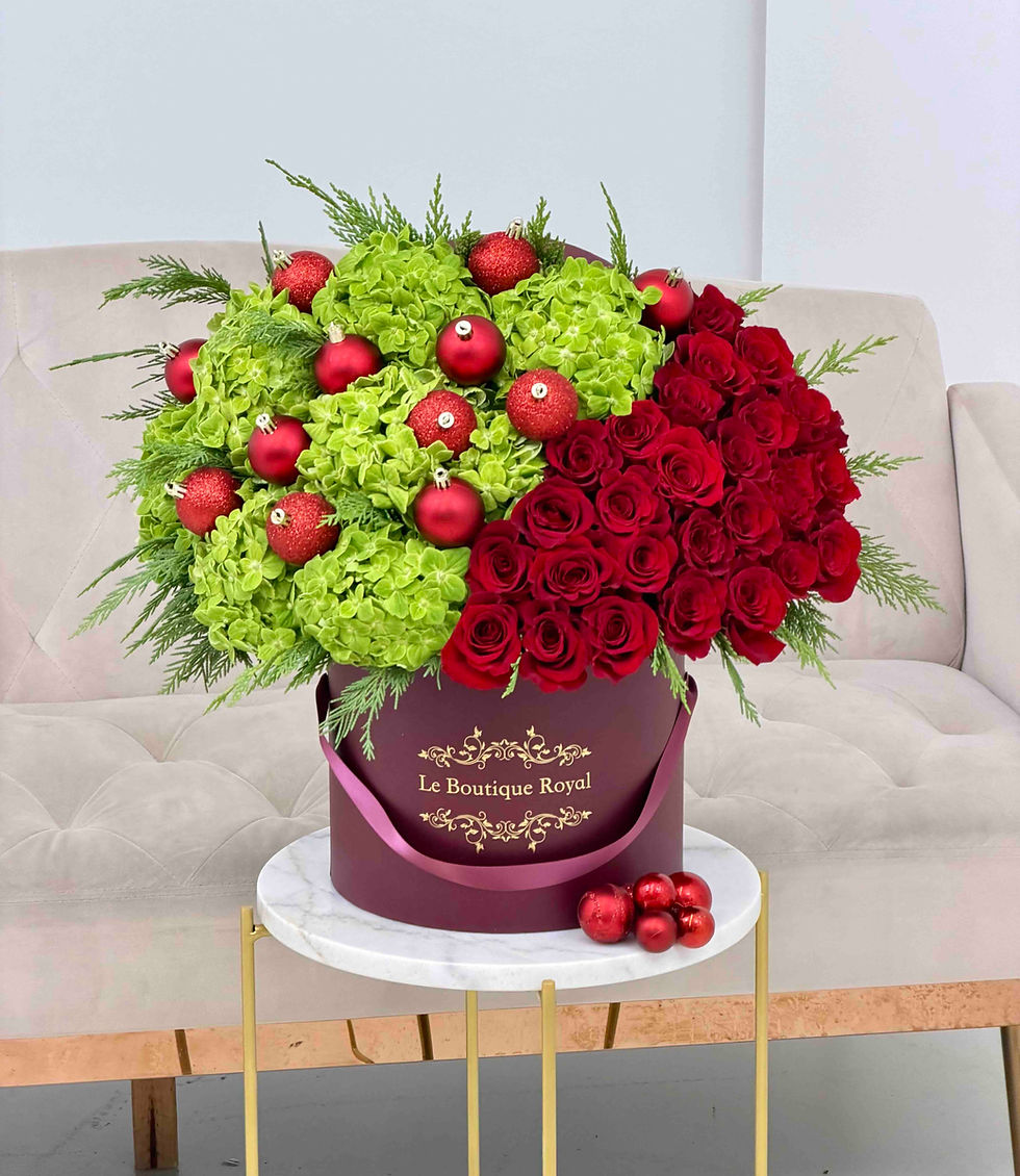 Holiday flower arrangement with red roses, green hydrangeas, red ornaments, and greenery