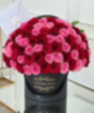 red and pink roses in a black vase