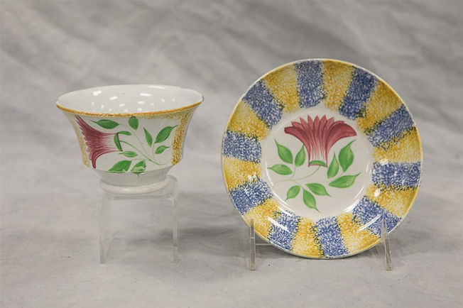 Blue and yellow rainbow spatter cup and saucer with thistle decoration