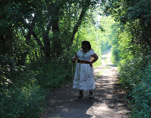 Photo of Brianna in the woods with her fiddle