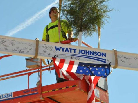 Wyatt Johnson celebrates Topping Out Ceremony - worker places final beam on top of new dealership