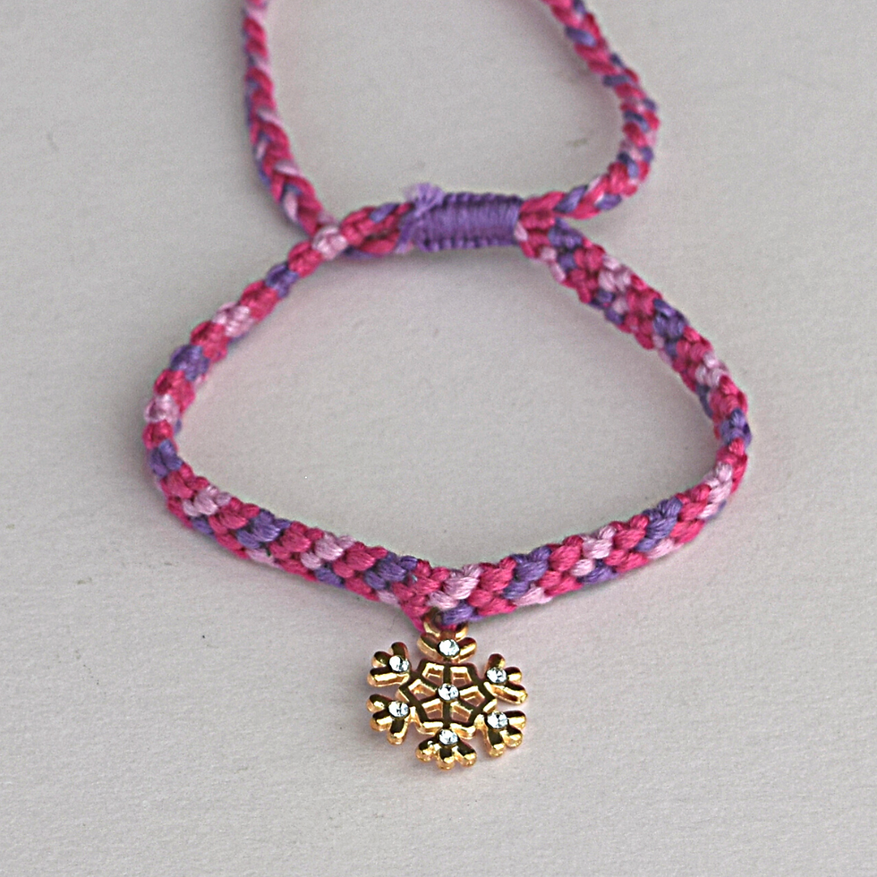pulsera navideña tejida en tonos morados con dije de copo de nieve