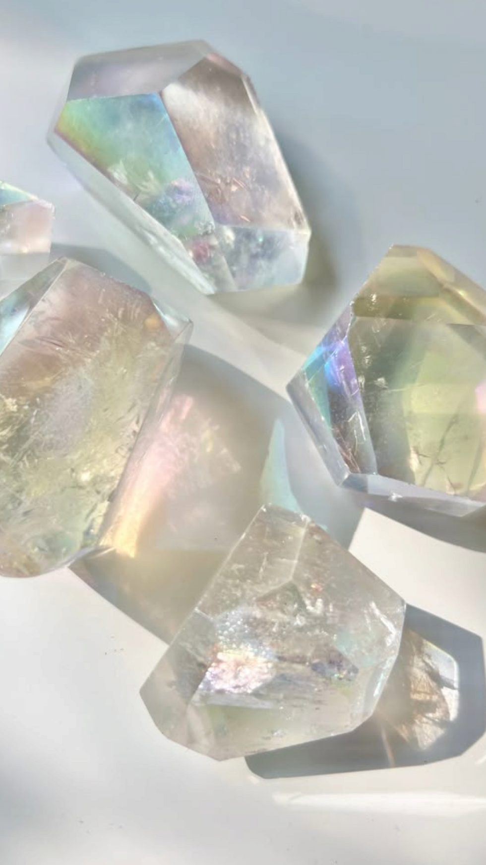 Iridescent clear quartz crystals with rainbow reflections in soft natural light on a minimal white background
