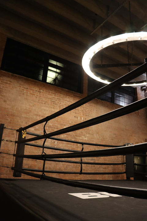 side view of the main boxing ring of the club with large led circle light illuminating the canvas