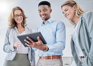 Foto de duas mulheres e um homem segundo um tablet