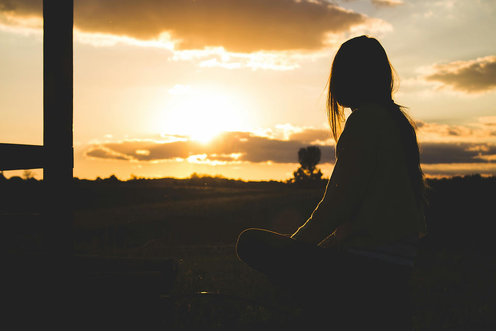 A woman stands quietly, gazing into a golden sunset with a reflective expression—symbolizing healing, hope, and the journey of processing trauma and reclaiming inner peace.