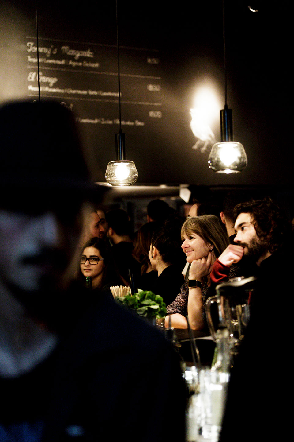 Mann mit Hut vor Gästen an Bar die auf Ihren Drink warten. Event Fotografie während Eröffnung neuer Bar in Basel