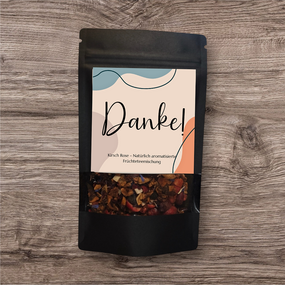 Miniaturbild: Tee in einer schwarzen, stehenden Verpackung mit Sichtfenster. Das Etikett trägt eine schlichte, elegante Gestaltung mit dem Schriftzug  'Danke' in stilvoller Schrift.