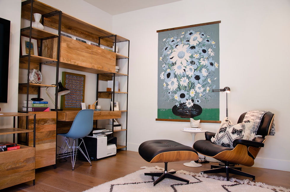 Coastal modern La Jolla interior design by Paschall Design. Here you see the office with an all in one desk shelfing and storage unit. Large flower art on the wall. A media console hold the TV and matches the desk. A white textual rug with black zig zags. Black and white pillows sit on top of the Herman Miller chair and ottoman. 