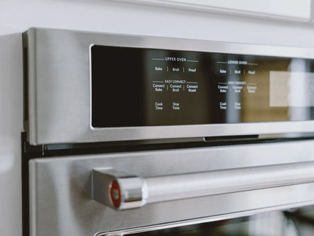 Stainless steel oven with digital display showing cooking options: Bake, Broil, Proof, Convection settings. Sleek modern kitchen setting.