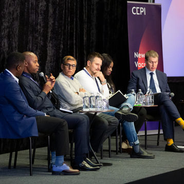 A panel of speakers on a stage in a conference.