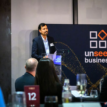 A speaker gives a keynote over an audience during an awards dinner