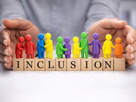 The word 'INCLUSION' spelled out on individual scrabble tiles, with colourful symbols of people atop and hands wrapping around the word 'INCLUSION'.