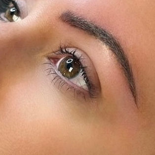 Close-up of combo brow permanent makeup showing a natural, fuller eyebrow with soft shading and hair-like detail.