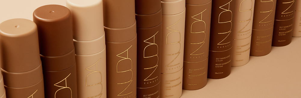Row of NUDA tanning mousse bottles in warm bronze packaging