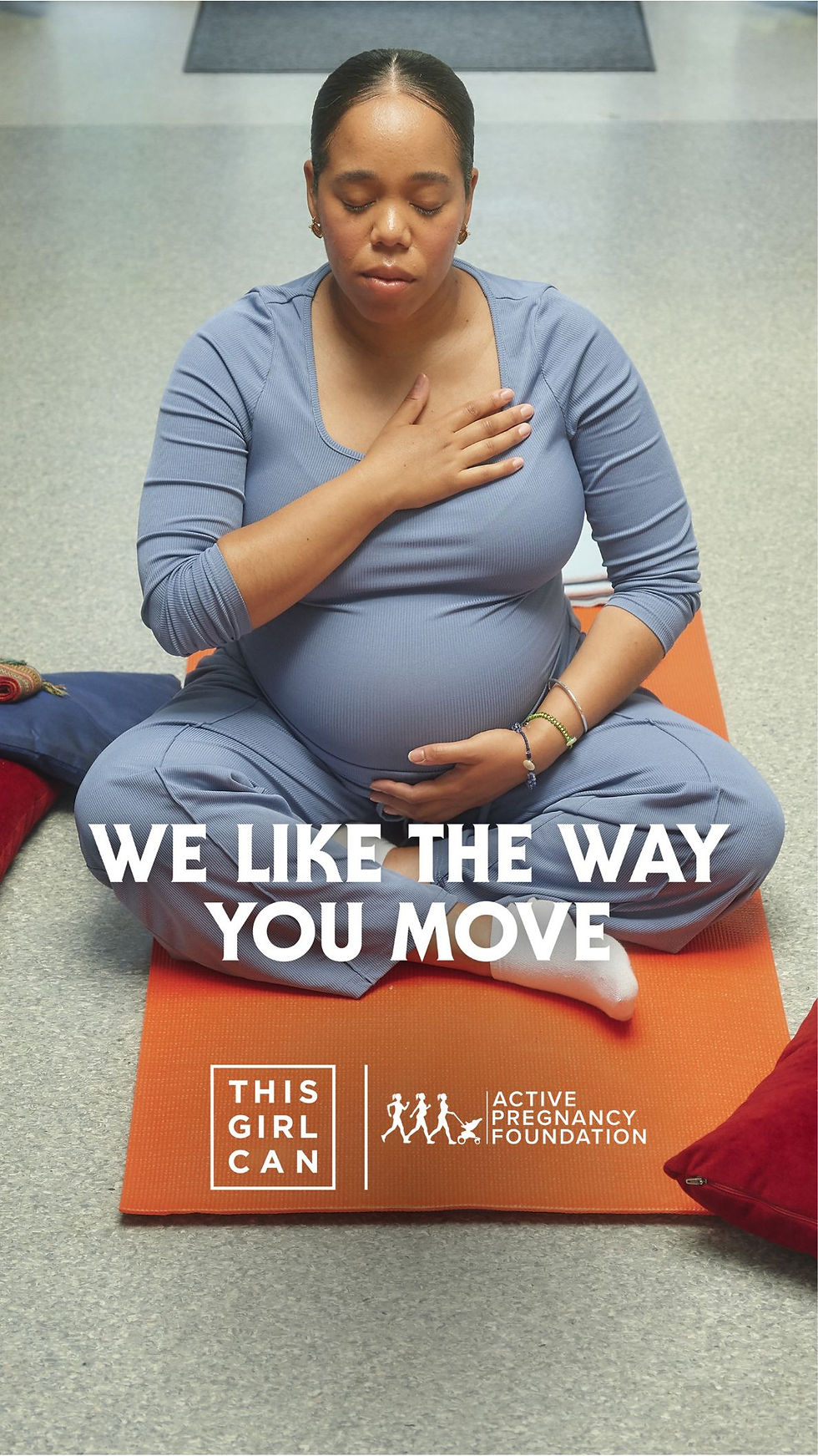 Pregnant woman meditating on an orange mat, hand on chest. Text: "WE LIKE THE WAY YOU MOVE." Calm setting, blue outfit.